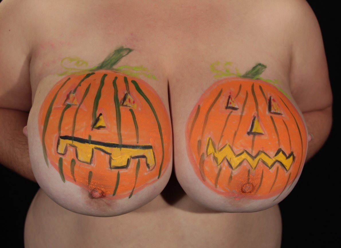 model with tripple D breasts, having one pumpkin painted on each breast