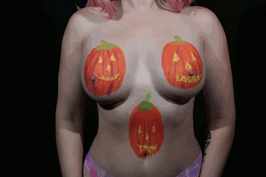 model with U V painted pumpkins on and between her breasts