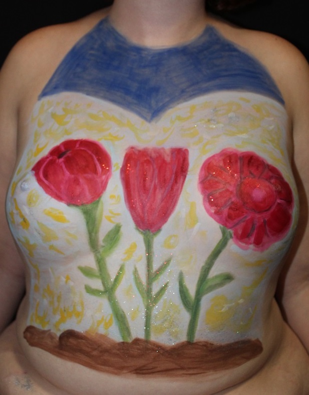 three red tulips growing from dirt on woman's torso