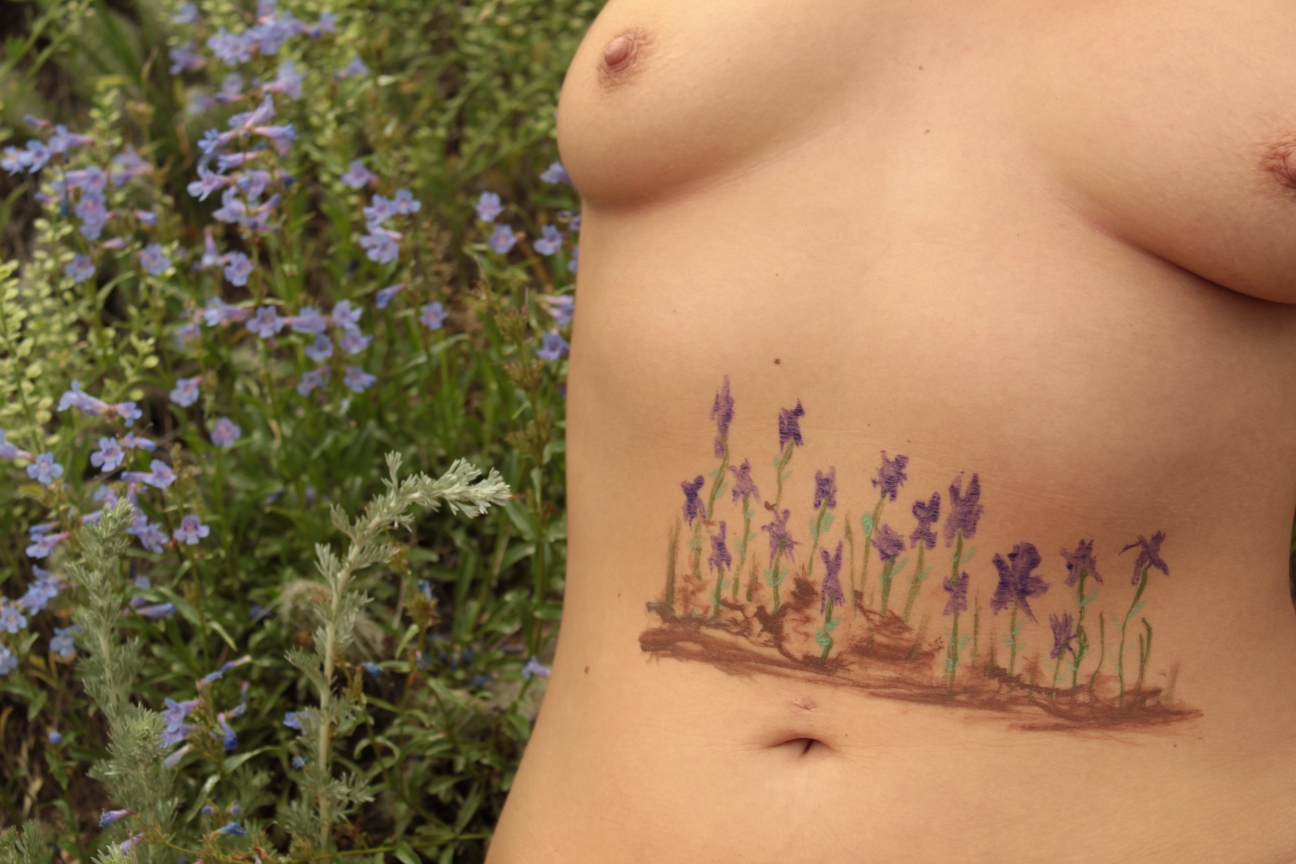 violets growing from dirt on woman's stomach
