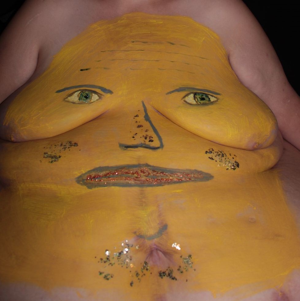 painting of yellow face on woman's torso
