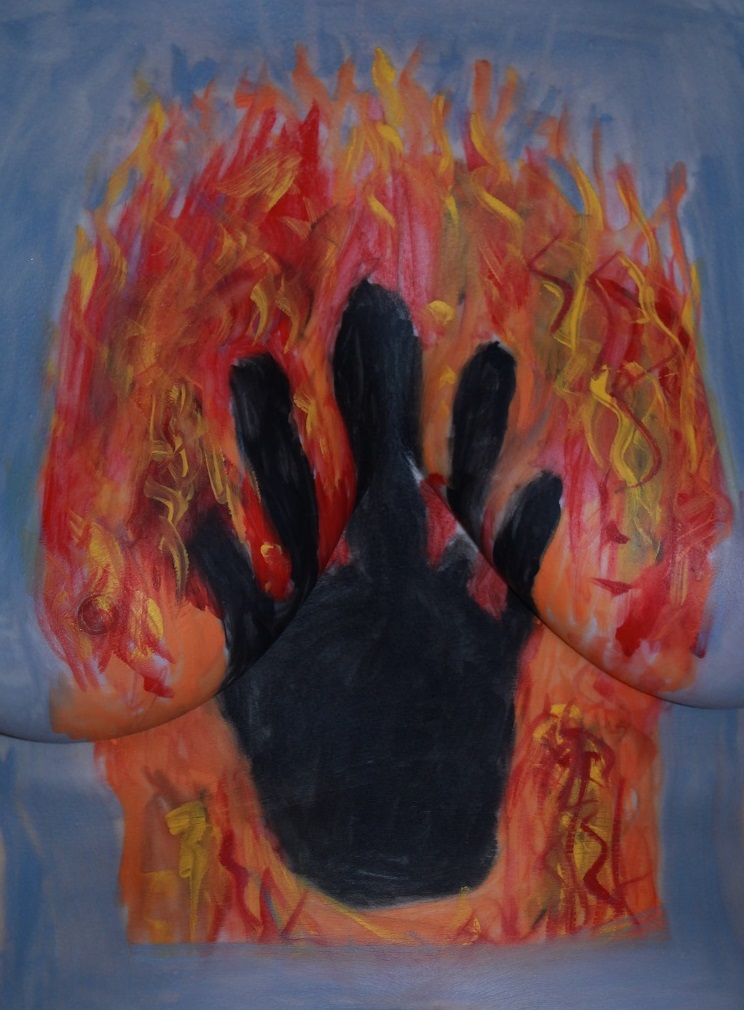 body painted silhouette of hand in a fire on woman's torso