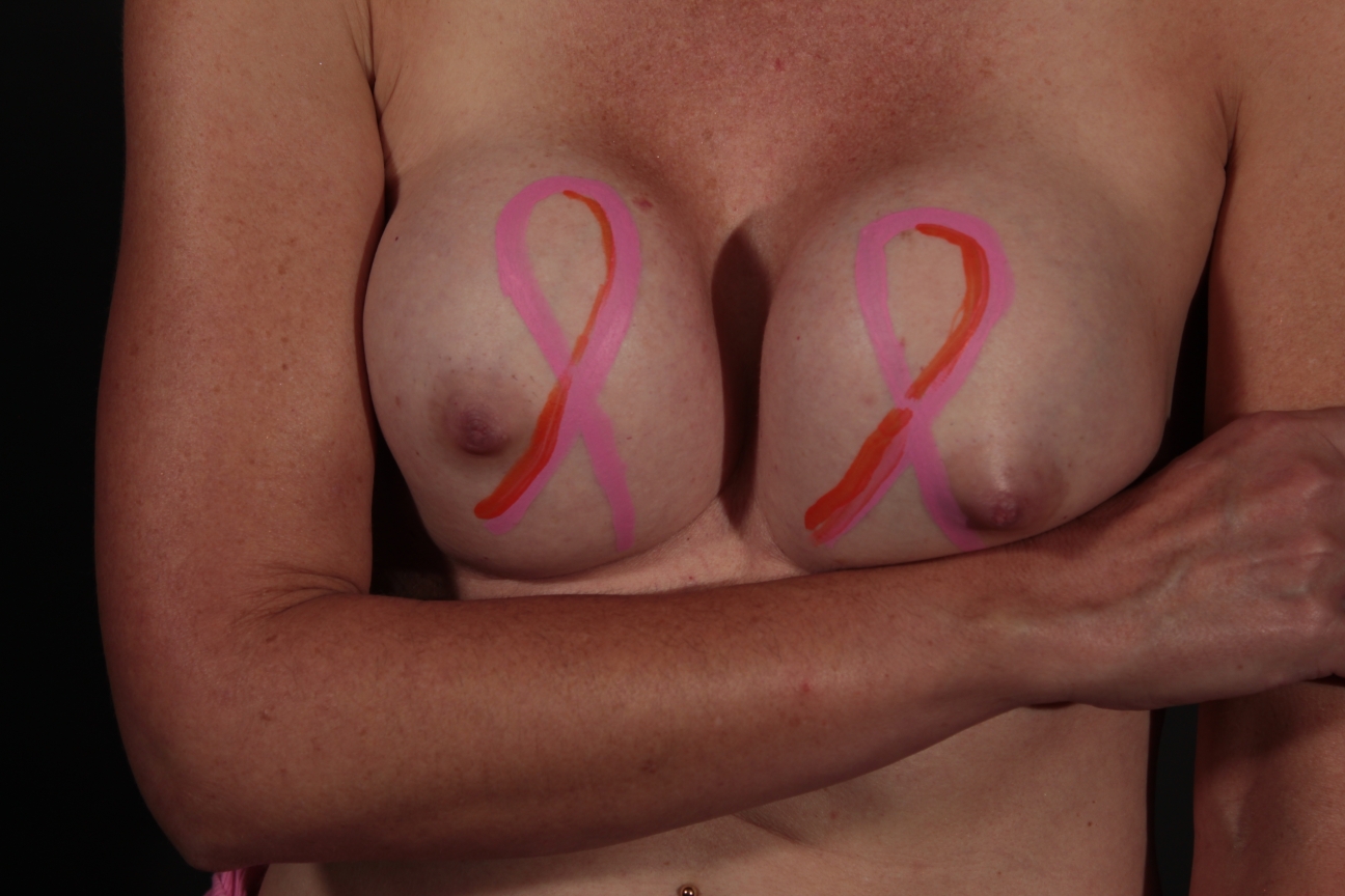 body painting of one pink ribbon on each of the woman's breasts