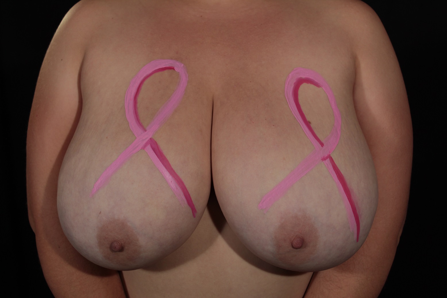 body painting of 2 pink ribbons, one on each of the woman's breasts