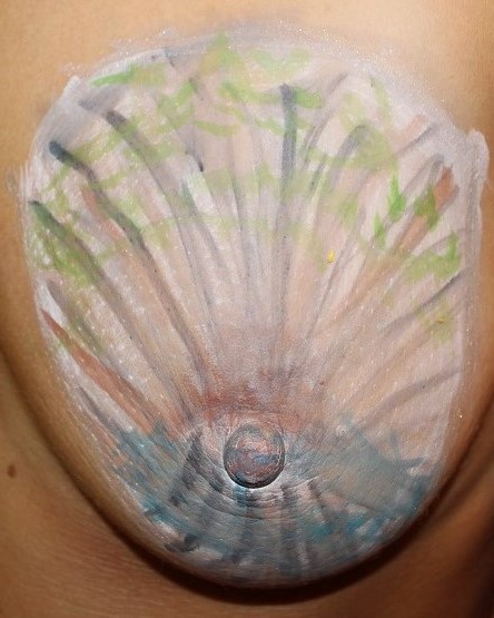 woman's left breast painted mostly white with blue below. Has green, black and brown lines radiating out from center