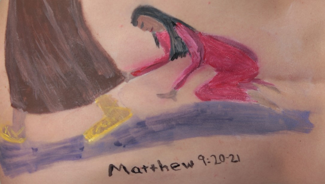 painting of Mary touching Jesus' hem, painted on model's back