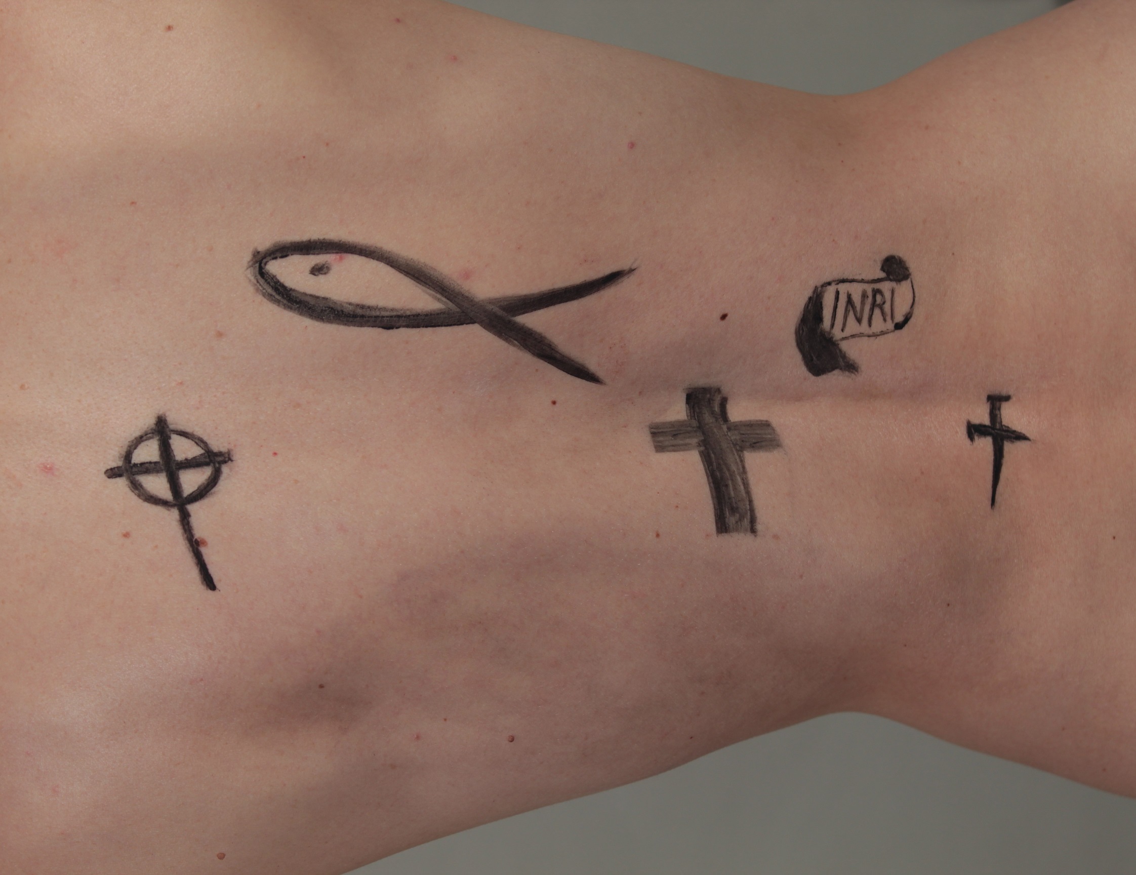 model with Christian symbols on her back: Cross, Fish, INRI Banner