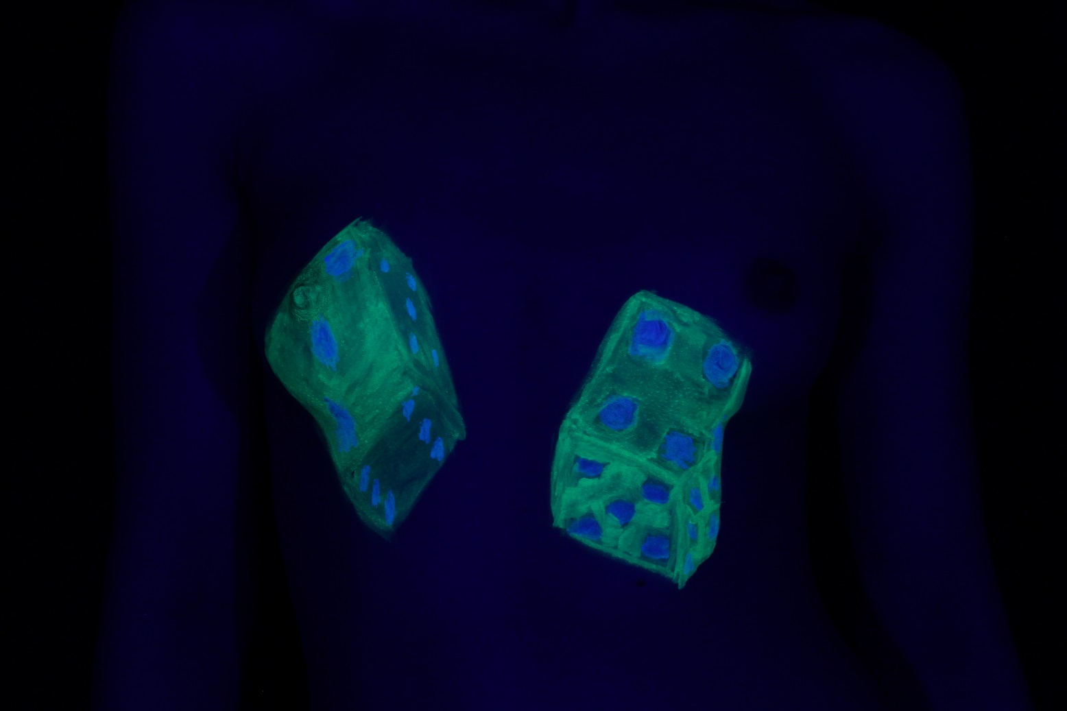 Dice painted on female breasts that glow in the U V ligthting.
