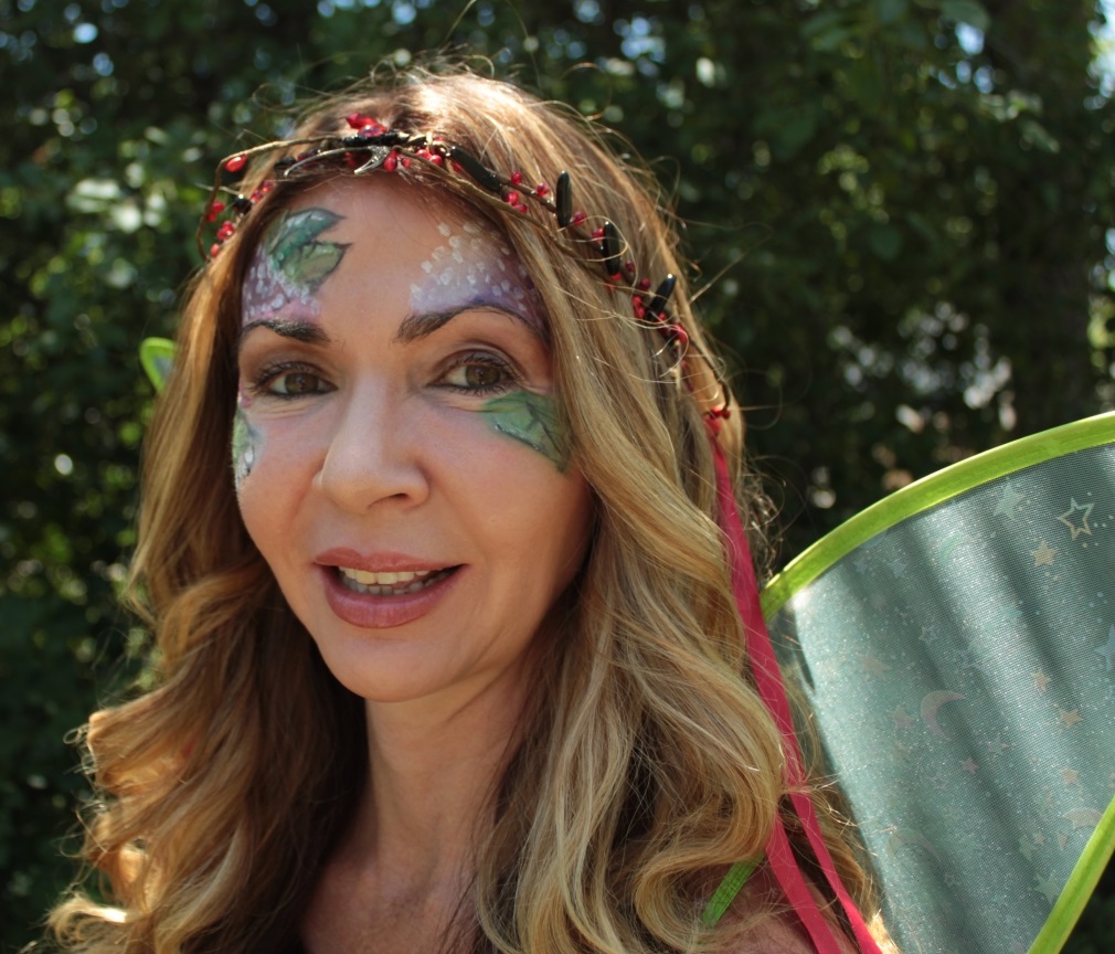 woman's face painted around the eyes in purple and green leaves
