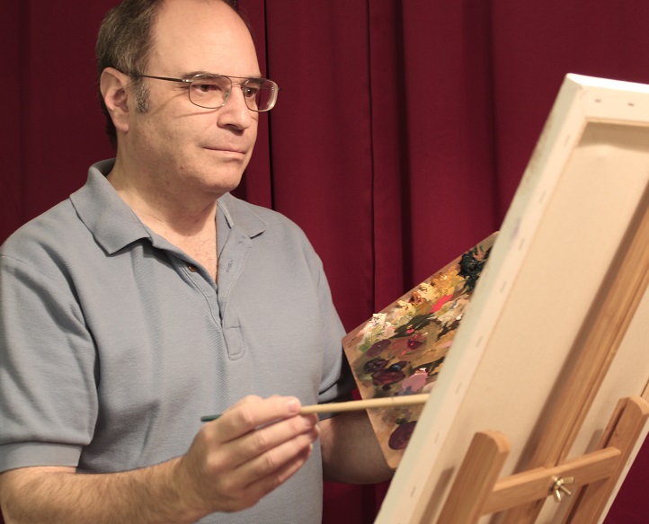 Photo of artist as he's painting an oil painting at an easel.