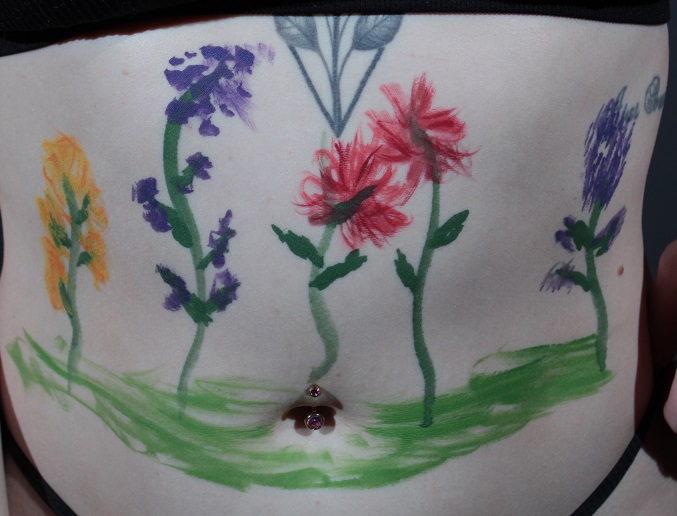 flowers growing from dirt on woman's stomach