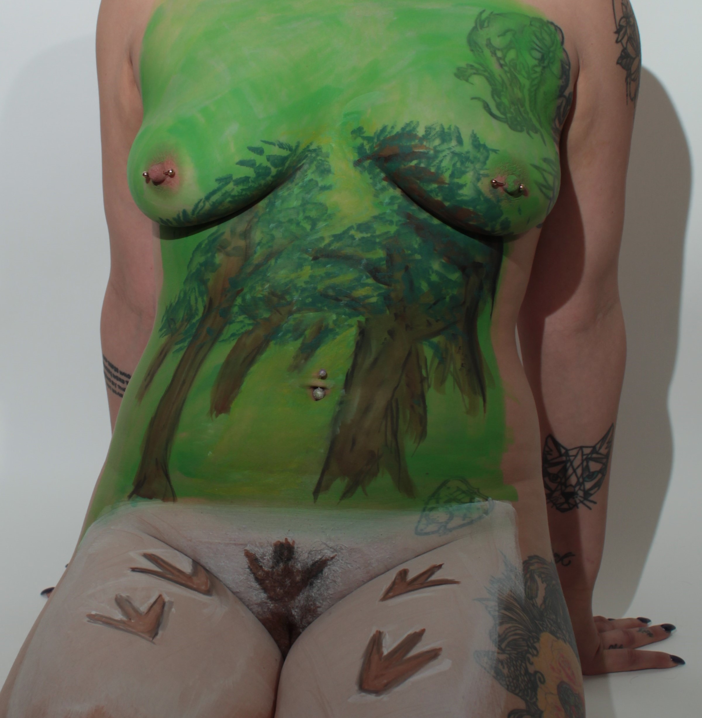 female torso painted ancient forest while her legs are painted with fosilized dinosaur tracks