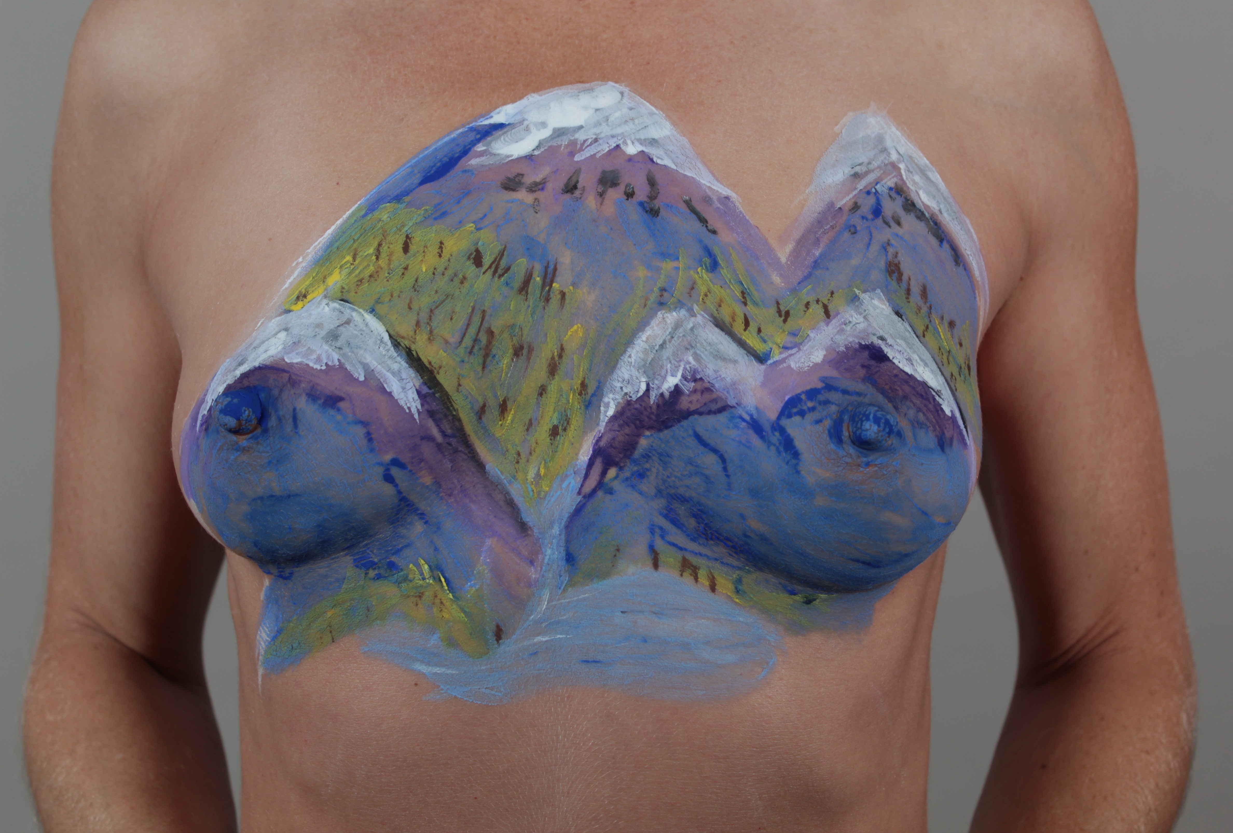 Range of mountains with a waterfall leading to a river on woman's chest