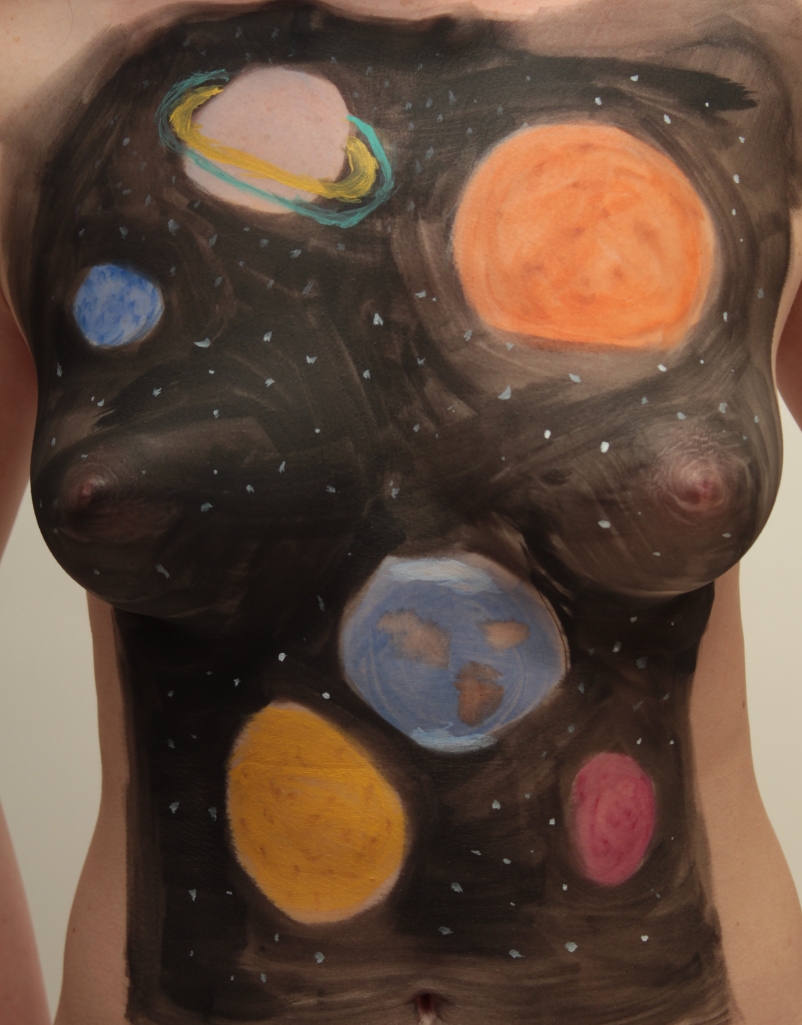 A few planets with stars body painted on a woman's torso