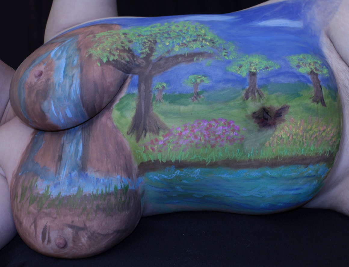 woman laying on side with water fall painted on breasts with river and trees on torso to the right