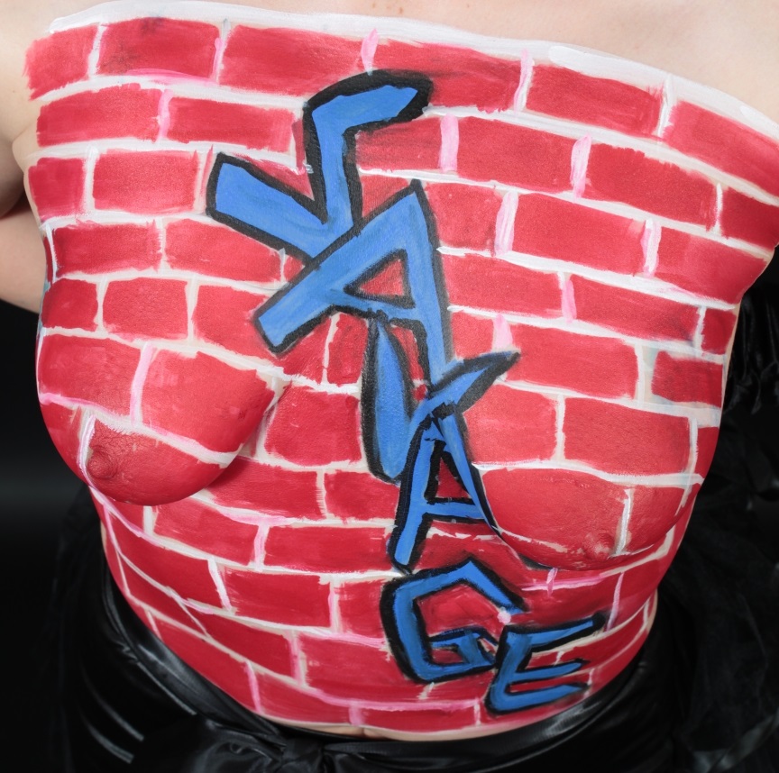 woman with brick wall and the word Savage in graffiti-style on her torso