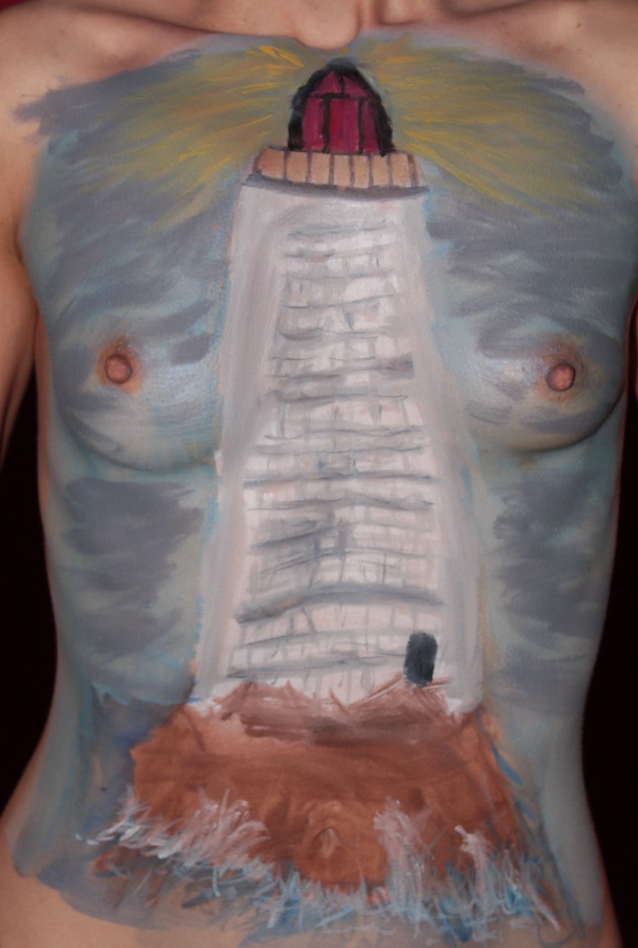 body painting on woman's torso of a lighthouse at night