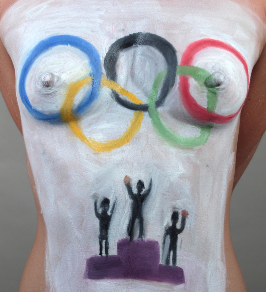 Closeup of Model with image of olympic rings painted across her breasts and podium with athletes painted on her stomach