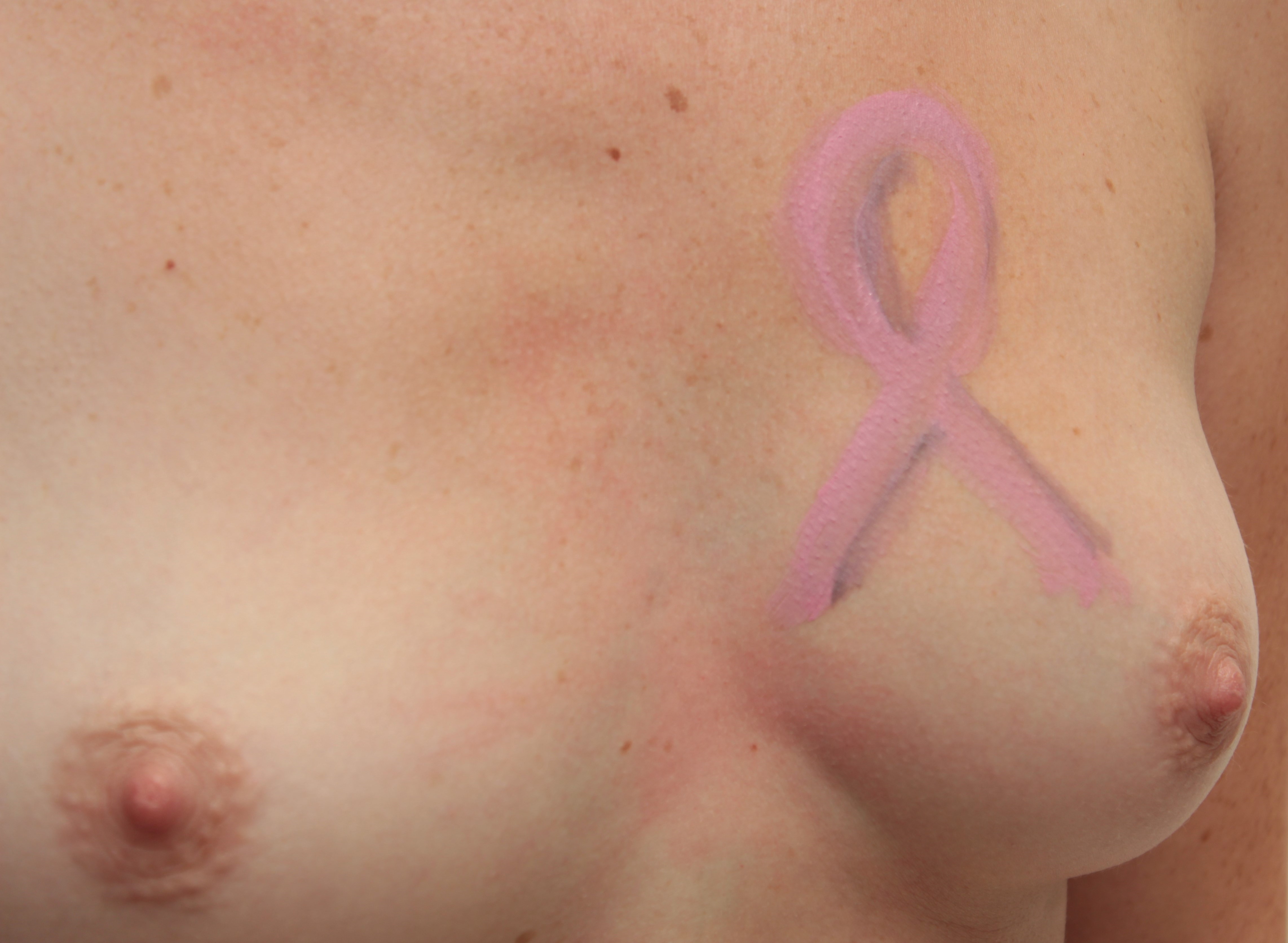 body painting of pink ribbon on woman's left breast