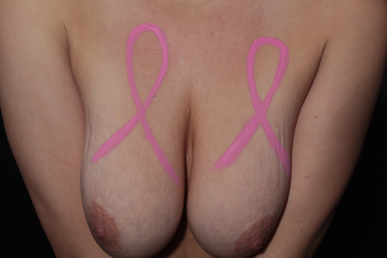 body painting of 2 pink ribbons, one on each of a woman's breasts