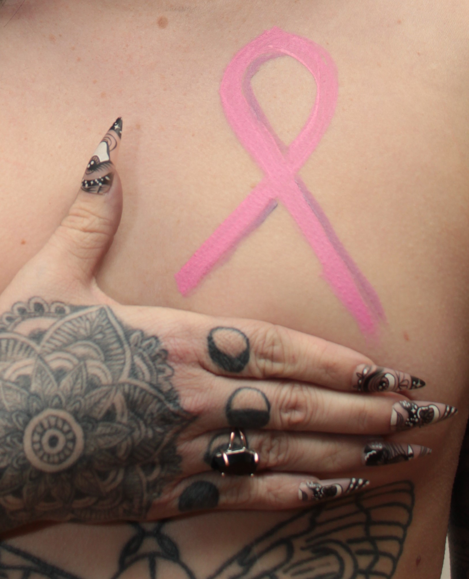body painting of pink ribbon on woman's breast